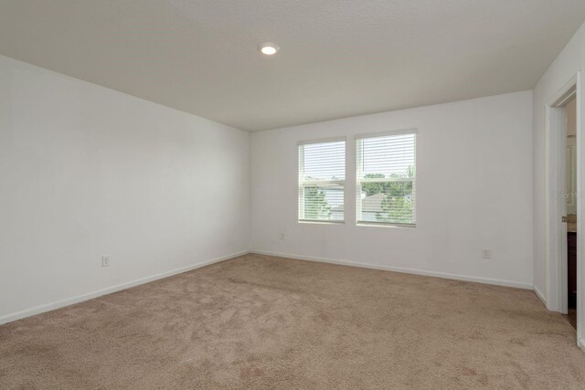 empty room with light colored carpet, baseboards, and recessed lighting