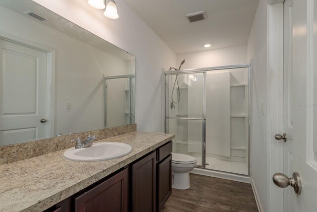 full bathroom with a shower stall, wood finished floors, vanity, and toilet