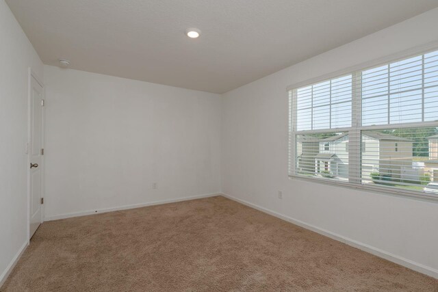 carpeted spare room featuring baseboards and recessed lighting