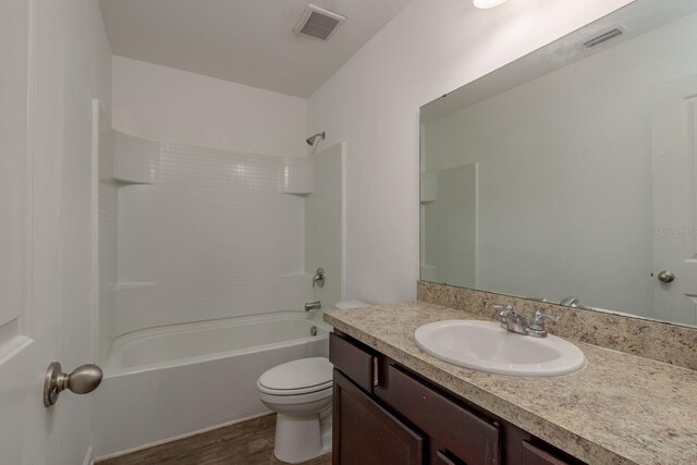 full bathroom featuring toilet, wood finished floors, vanity, and shower / washtub combination
