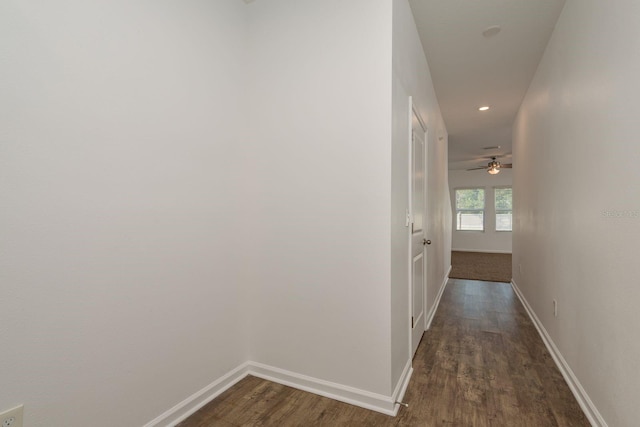 hallway featuring dark wood-type flooring, baseboards, and recessed lighting