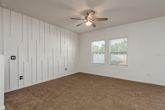 empty room with ceiling fan, dark carpet, and baseboards