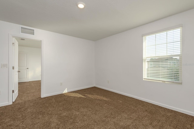 empty room featuring carpet and baseboards