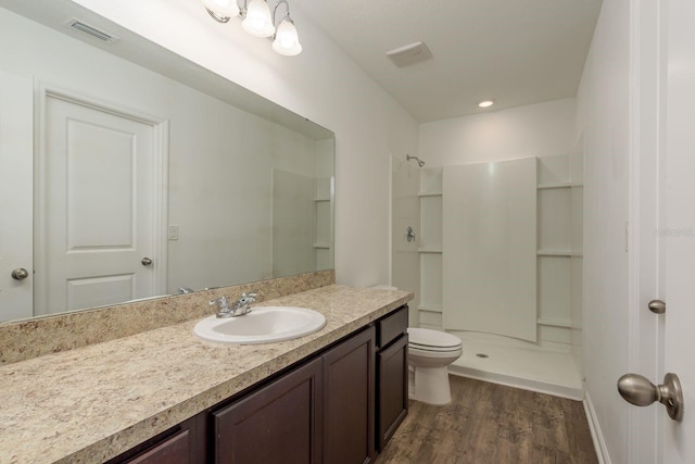 full bathroom featuring wood finished floors, a stall shower, toilet, and vanity