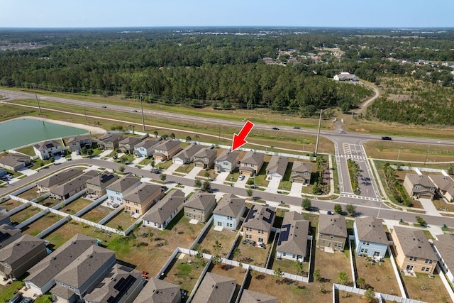 view of property location with a forest, nearby suburban area, and a large body of water