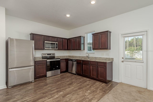 kitchen with appliances with stainless steel finishes, a sink, dark brown cabinetry, healthy amount of natural light, and recessed lighting
