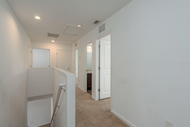 hall with an upstairs landing, light colored carpet, recessed lighting, attic access, and baseboards