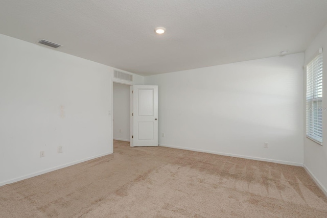 empty room featuring light colored carpet and baseboards