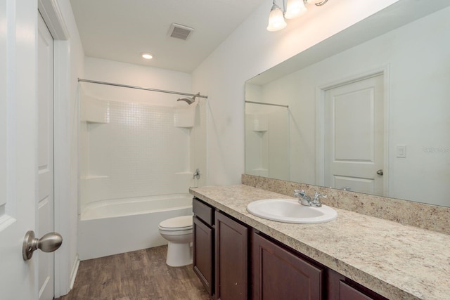 bathroom featuring wood finished floors, toilet, vanity, and shower / bathtub combination