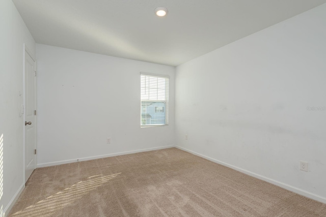 spare room featuring baseboards and light carpet