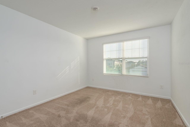 empty room featuring light carpet and baseboards