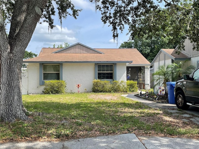 view of front of house featuring a shingled roof, stucco siding, and a front yard