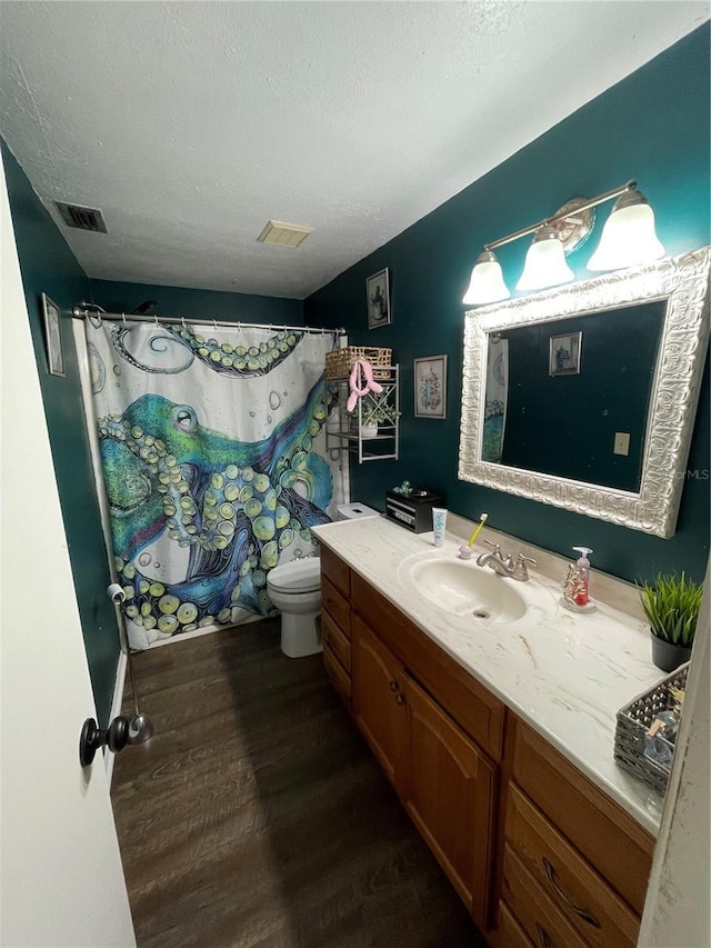bathroom with toilet, visible vents, wood finished floors, and vanity