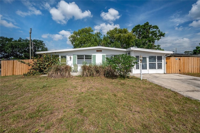 view of front of property featuring fence, concrete driveway, and a front yard
