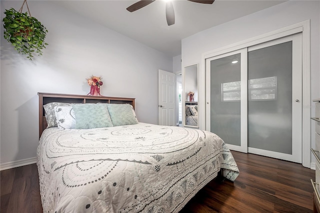 bedroom featuring baseboards, dark wood finished floors, ceiling fan, and a closet