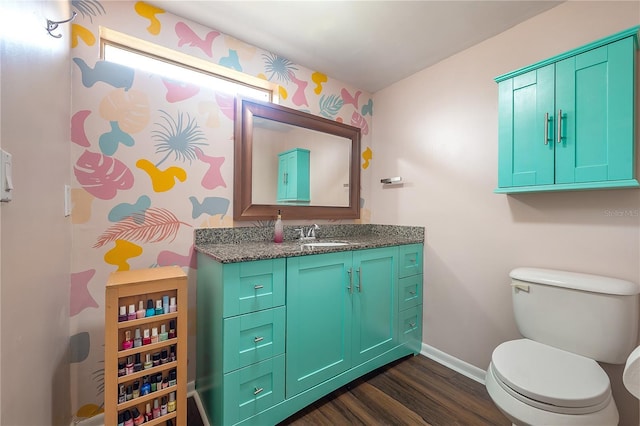 half bathroom with toilet, baseboards, wood finished floors, and vanity