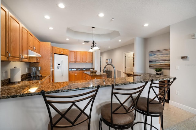 17735 Gulf Blvd Unit 304, Redington Shores, FL 33708 - kitchen featuring white fridge with ice dispenser, under cabinet range hood, recessed lighting, a peninsula, and light tile patterned floors