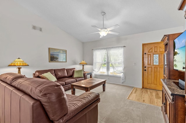 living room featuring light colored carpet, a ceiling fan, lofted ceiling, a textured ceiling, and baseboards