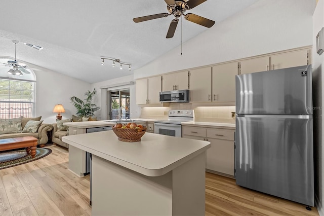 kitchen with appliances with stainless steel finishes, ceiling fan, lofted ceiling, light countertops, and a sink