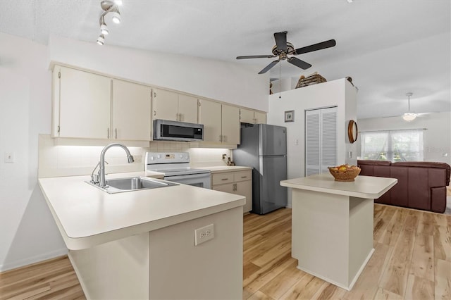 kitchen featuring stainless steel appliances, a sink, a ceiling fan, light countertops, and vaulted ceiling
