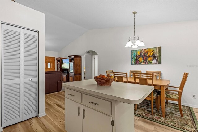 kitchen with lofted ceiling, light wood finished floors, a chandelier, light countertops, and hanging light fixtures