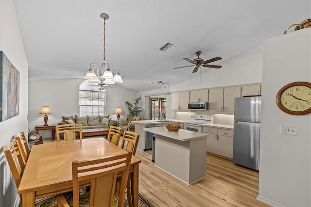 kitchen featuring appliances with stainless steel finishes, light countertops, lofted ceiling, ceiling fan, and a chandelier