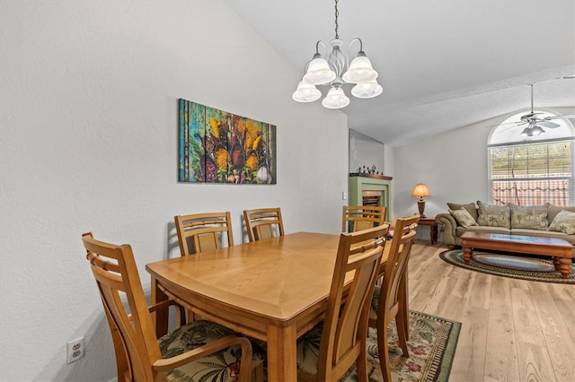 dining room with vaulted ceiling, a chandelier, and light wood-style flooring
