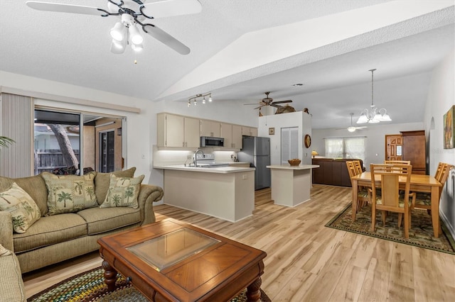 living area featuring a ceiling fan, lofted ceiling, light wood finished floors, and a chandelier
