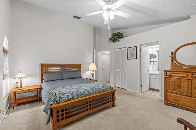 bedroom featuring light carpet, vaulted ceiling, ensuite bath, a closet, and baseboards