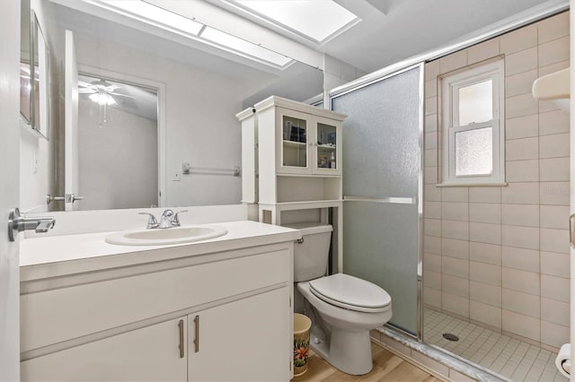 full bathroom with a shower stall, toilet, wood finished floors, and vanity