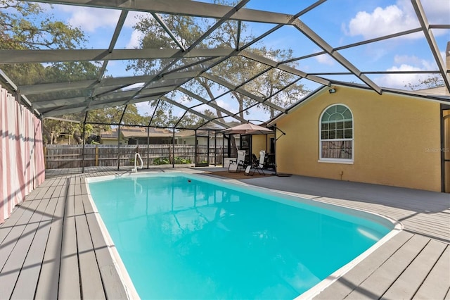 view of swimming pool featuring a deck, fence, and a lanai