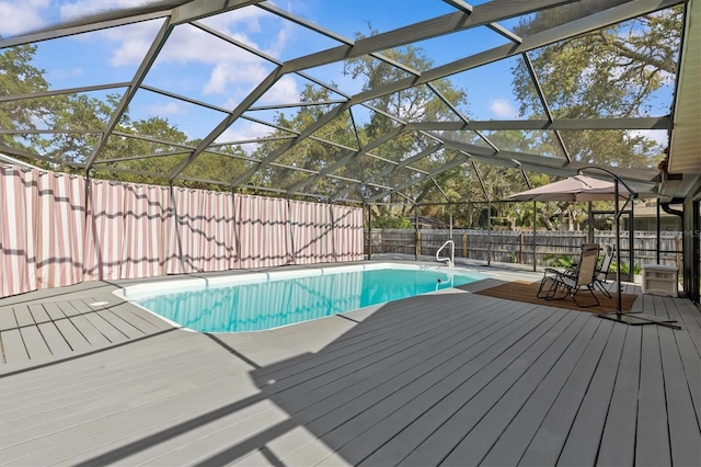 view of swimming pool featuring a wooden deck, a fenced backyard, and a lanai