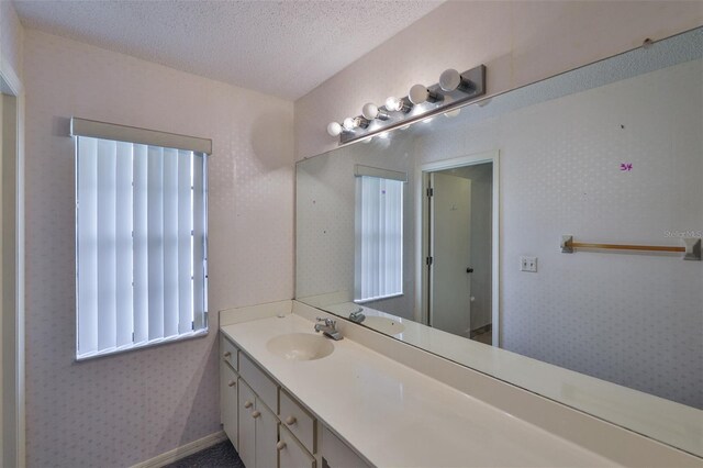 1915 W Del Webb Blvd, Sun City Center, FL 33573 - bathroom with vanity, wallpapered walls, healthy amount of natural light, and a textured ceiling