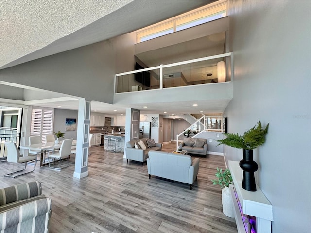1390 Gulf Blvd Unit Ph-5, Clearwater, FL 33767 - living area featuring baseboards, stairs, light wood-type flooring, a towering ceiling, and recessed lighting