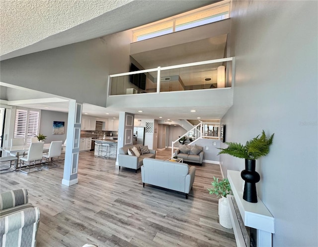 1390 Gulf Blvd Unit Ph-5, Clearwater, FL 33767 - living room with a towering ceiling, baseboards, light wood-style flooring, stairway, and recessed lighting