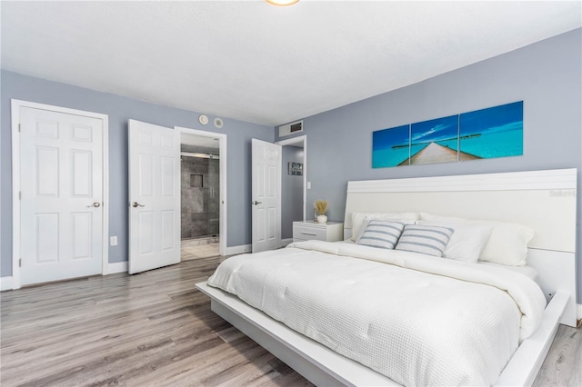1390 Gulf Blvd Unit Ph-5, Clearwater, FL 33767 - bedroom featuring baseboards, wood finished floors, and connected bathroom