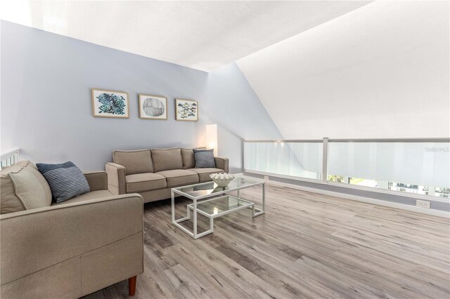 1390 Gulf Blvd Unit Ph-5, Clearwater, FL 33767 - living room featuring wood finished floors, vaulted ceiling, and baseboards