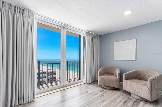 1390 Gulf Blvd Unit Ph-5, Clearwater, FL 33767 - sitting room featuring wood finished floors, a water view, and a textured ceiling