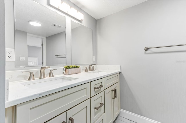 1390 Gulf Blvd Unit Ph-5, Clearwater, FL 33767 - bathroom featuring double vanity, baseboards, and a textured ceiling