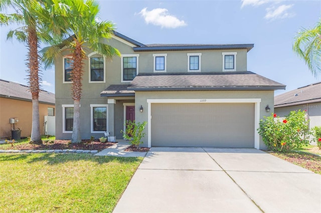 traditional-style house with a front lawn, concrete driveway, an attached garage, a shingled roof, and stucco siding