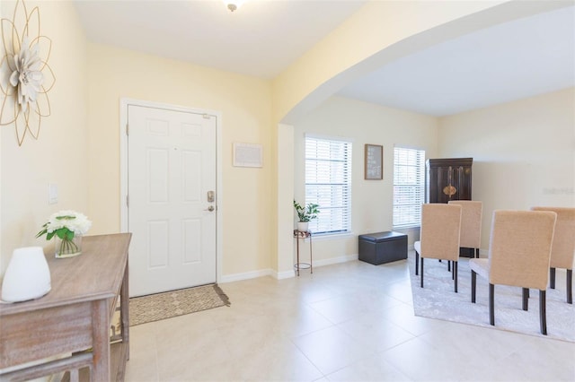 foyer with baseboards, arched walkways, and light tile patterned floors