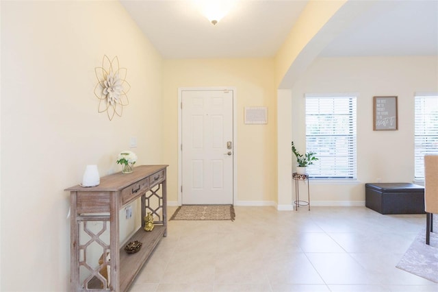 entryway featuring baseboards, arched walkways, and light tile patterned flooring