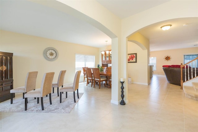 dining space featuring stairs, arched walkways, a chandelier, and plenty of natural light