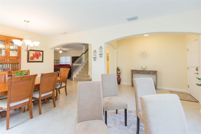 dining space featuring visible vents, arched walkways, a notable chandelier, and stairway