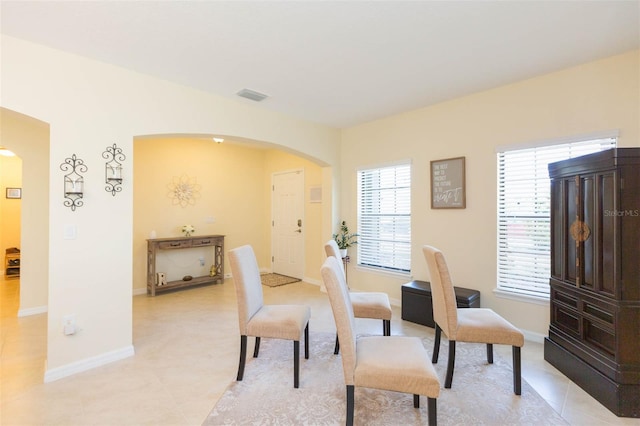 dining room featuring visible vents, arched walkways, baseboards, and light tile patterned floors