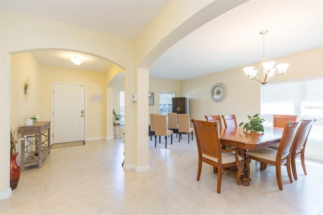 dining area featuring a healthy amount of sunlight, arched walkways, baseboards, and a notable chandelier
