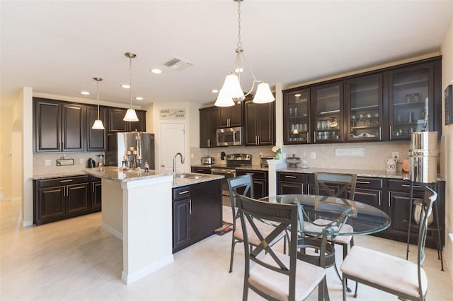 kitchen featuring backsplash, stainless steel appliances, dark brown cabinetry, and a sink