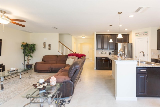 living area featuring ceiling fan, visible vents, arched walkways, stairway, and light tile patterned flooring