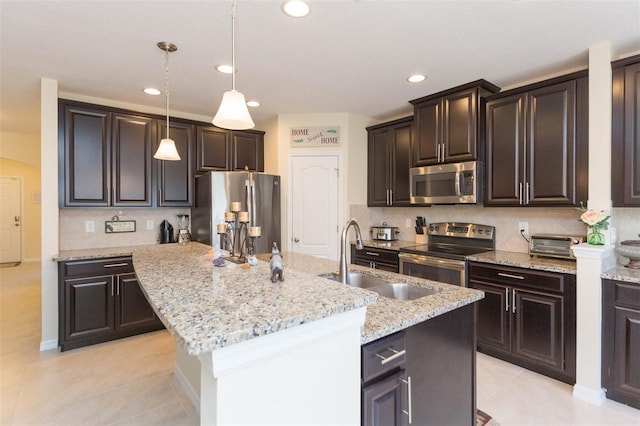 kitchen with a sink, appliances with stainless steel finishes, tasteful backsplash, and a kitchen island with sink