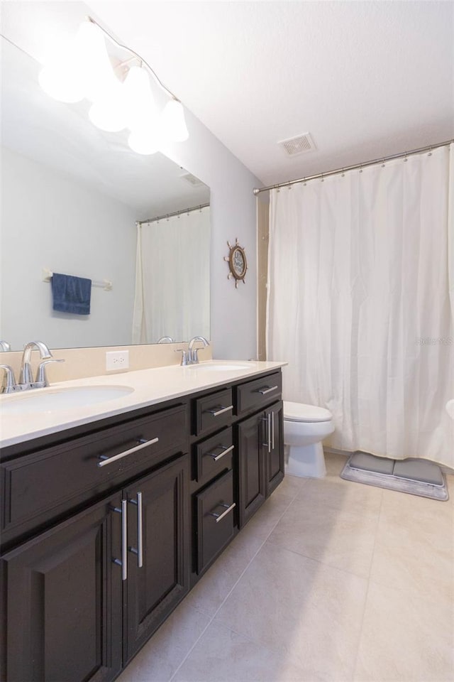 bathroom featuring a sink, tile patterned flooring, toilet, and double vanity